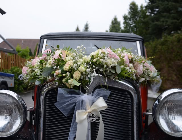 Blumengirlande aus Rosen auf der Motorhaube eines Hochzeitsautos