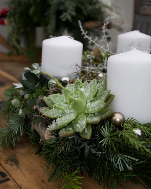 Weiße Tischdekoration mit Kerzen und einer frostigen Sukkulente